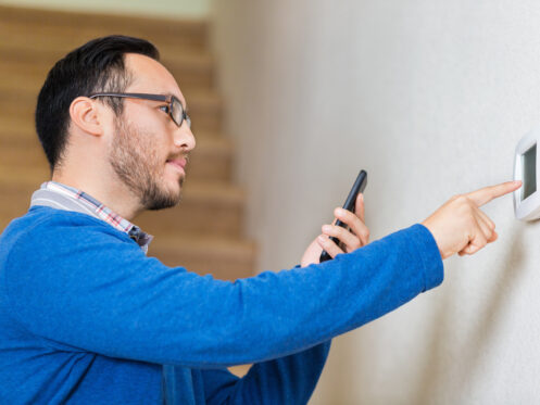 Man adjusting thermostat downstairs